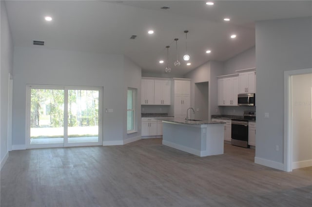 kitchen featuring a kitchen island with sink, high vaulted ceiling, appliances with stainless steel finishes, decorative light fixtures, and white cabinetry