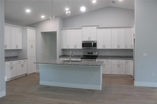 kitchen with appliances with stainless steel finishes, vaulted ceiling, sink, white cabinets, and hanging light fixtures