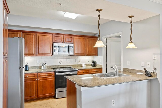 kitchen with appliances with stainless steel finishes, decorative backsplash, kitchen peninsula, pendant lighting, and sink