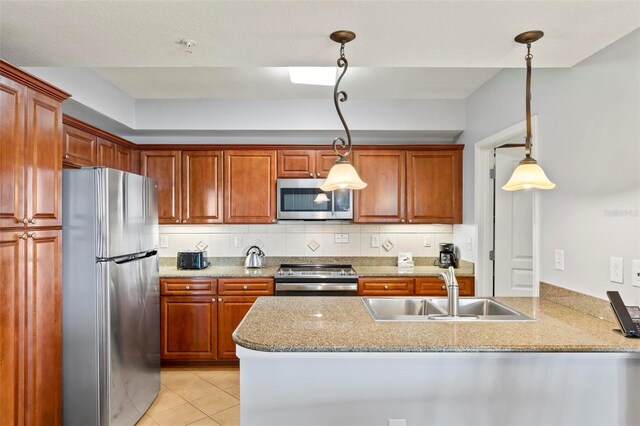 kitchen featuring tasteful backsplash, kitchen peninsula, pendant lighting, stainless steel appliances, and sink