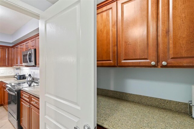 kitchen featuring appliances with stainless steel finishes, light tile patterned floors, and light stone counters