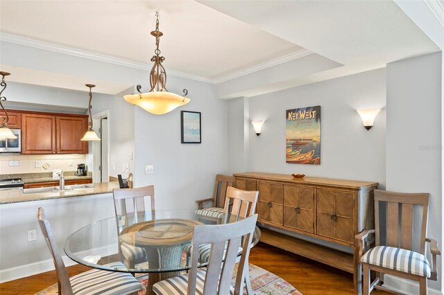 dining area with ornamental molding, sink, and dark wood-type flooring