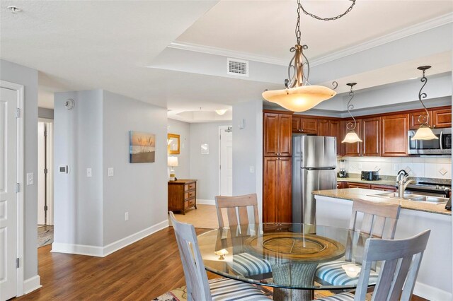 dining room with ornamental molding, hardwood / wood-style flooring, and sink