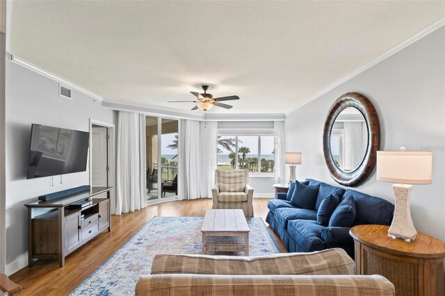 living room with ceiling fan, a textured ceiling, crown molding, and light hardwood / wood-style floors