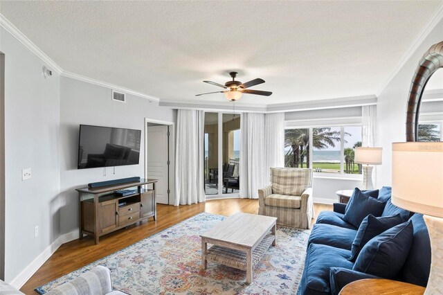 living room with a textured ceiling, crown molding, light hardwood / wood-style floors, and ceiling fan