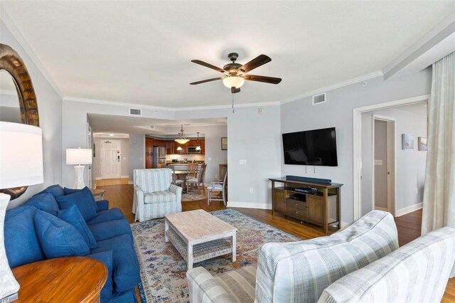 living room with crown molding, wood-type flooring, and ceiling fan