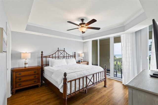 bedroom featuring ceiling fan, a raised ceiling, ornamental molding, dark hardwood / wood-style floors, and access to exterior