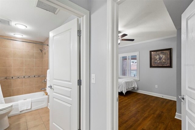 bathroom with wood-type flooring, crown molding, ceiling fan, shower / tub combo with curtain, and toilet