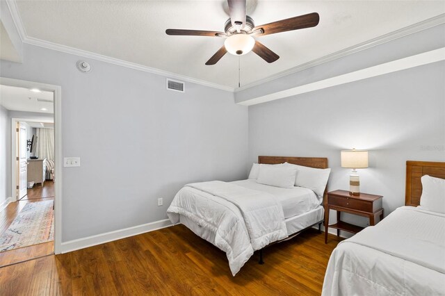 bedroom with ceiling fan, crown molding, and dark wood-type flooring