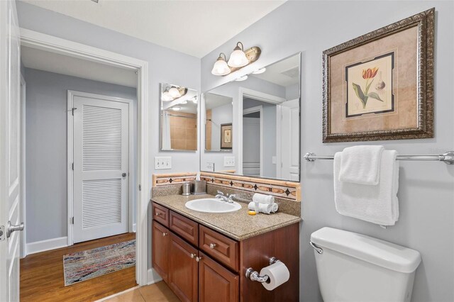 bathroom featuring wood-type flooring, vanity, and toilet