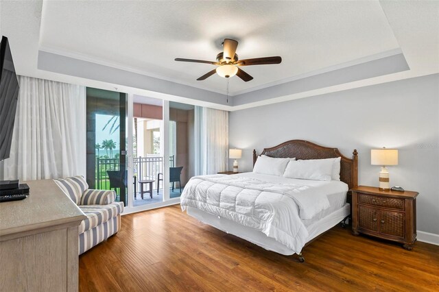 bedroom with a raised ceiling, dark hardwood / wood-style flooring, ceiling fan, and access to exterior