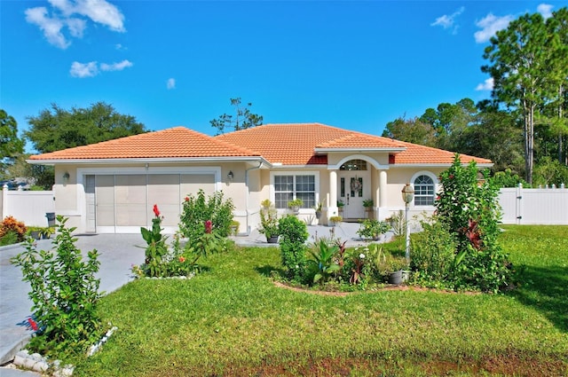 mediterranean / spanish-style home with a garage and a front lawn