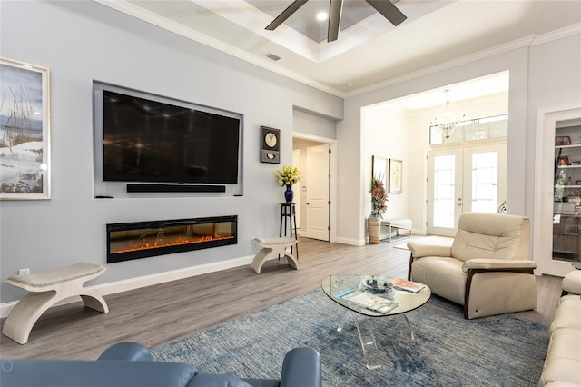 living room featuring crown molding, light hardwood / wood-style flooring, and ceiling fan with notable chandelier