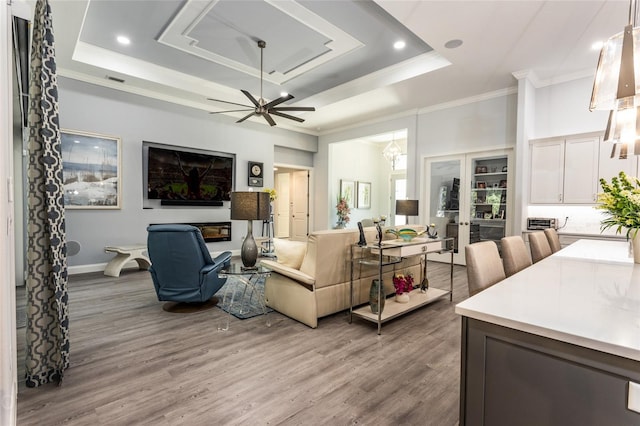 living room featuring ceiling fan, hardwood / wood-style flooring, and a raised ceiling