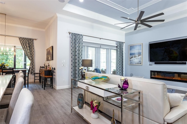 living room with ceiling fan, wood-type flooring, a wealth of natural light, and ornamental molding