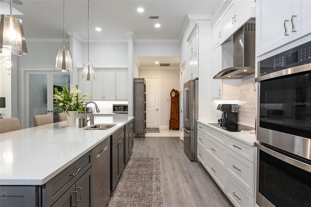 kitchen featuring hanging light fixtures, white cabinetry, sink, stainless steel appliances, and ventilation hood