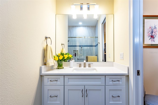 bathroom featuring a shower with door and vanity