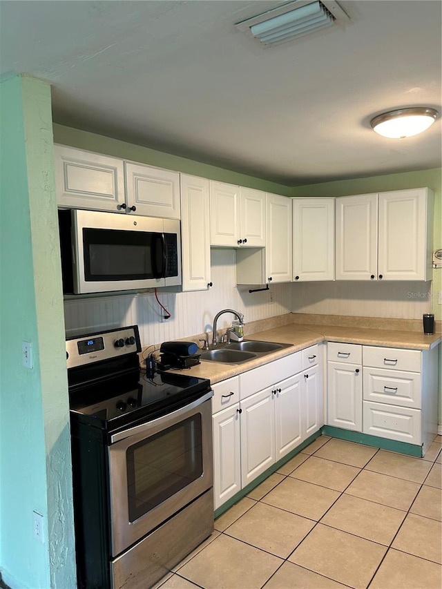 kitchen with light tile patterned floors, white cabinets, stainless steel appliances, and sink