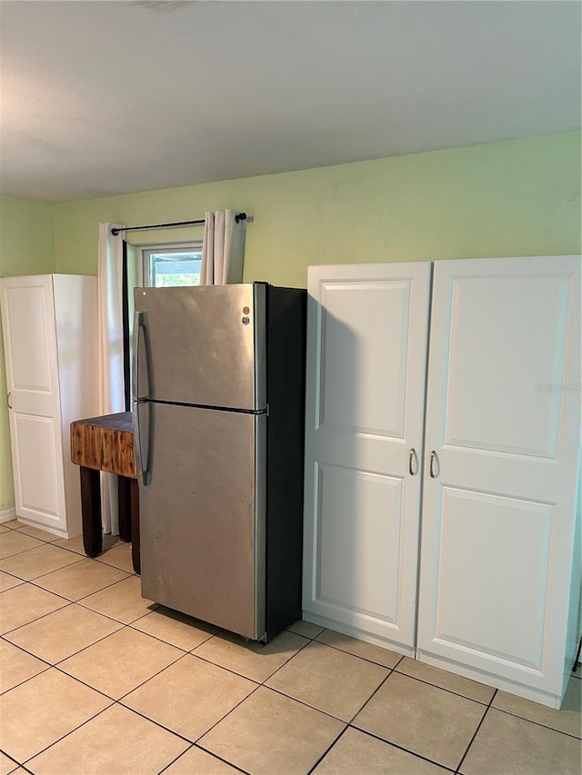 kitchen with white cabinetry, light tile patterned floors, and stainless steel fridge