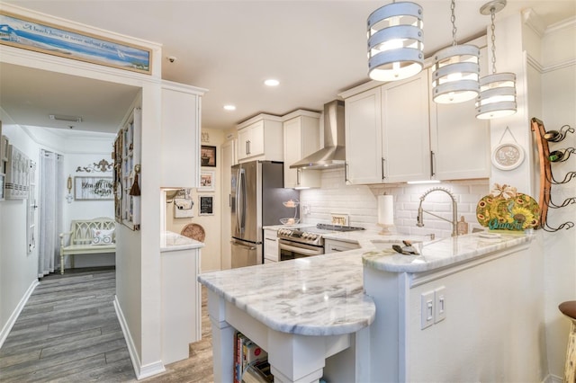 110 Ocean Hollow Ln Unit 101, Saint Augustine, FL 32084 - kitchen with wall chimney range hood, appliances with stainless steel finishes, wood finished floors, tasteful backsplash, and white cabinets