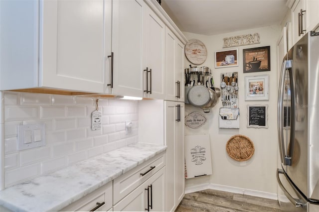110 Ocean Hollow Ln Unit 101, Saint Augustine, FL 32084 - kitchen with freestanding refrigerator, tasteful backsplash, light wood-style floors, white cabinetry, and light stone countertops