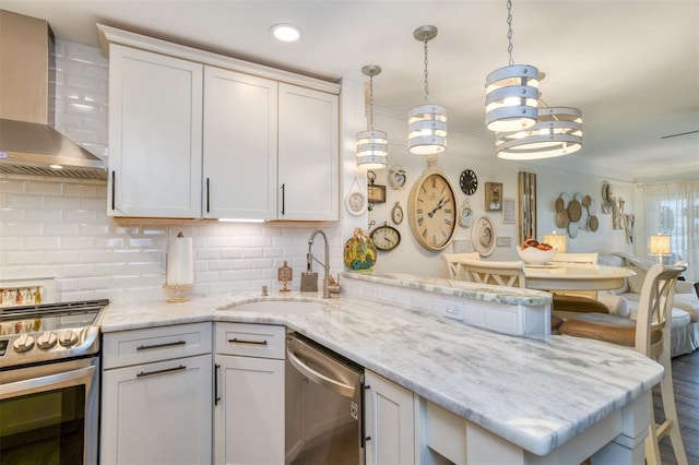 110 Ocean Hollow Ln Unit 101, Saint Augustine, FL 32084 - kitchen featuring stainless steel appliances, wall chimney range hood, a peninsula, decorative backsplash, and a breakfast bar area