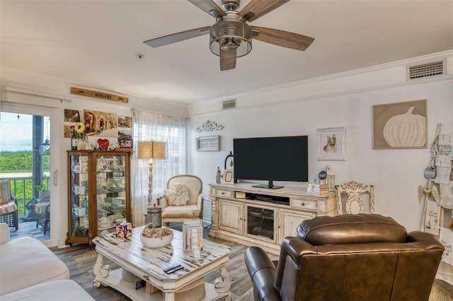 living room with wood-type flooring, crown molding, and ceiling fan