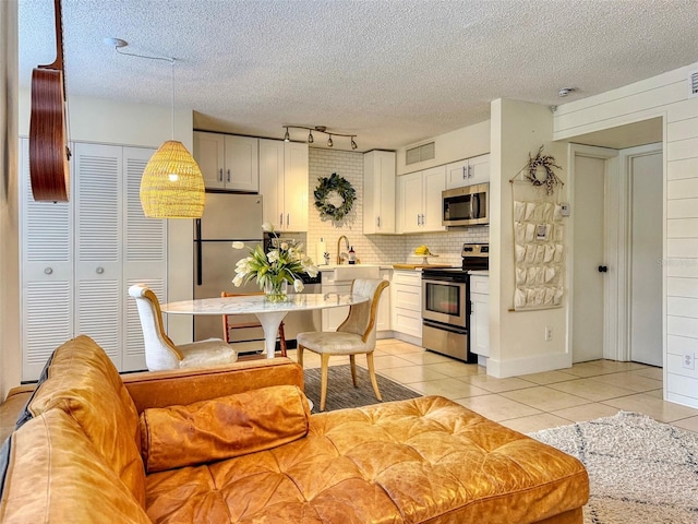 interior space with pendant lighting, stainless steel appliances, white cabinets, and light tile patterned flooring