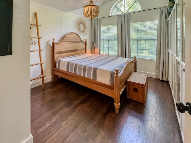 bedroom featuring an inviting chandelier and dark hardwood / wood-style flooring