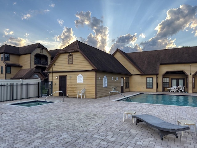 pool at dusk featuring a community hot tub and a patio area