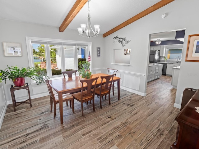 dining space featuring vaulted ceiling with beams, light hardwood / wood-style floors, sink, and a chandelier