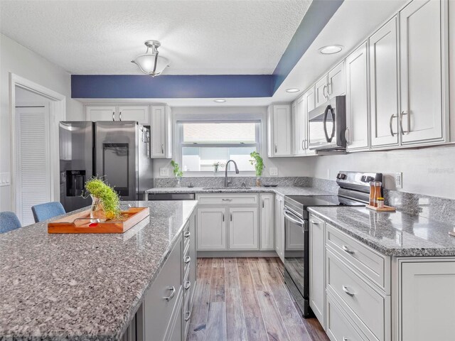 kitchen featuring sink, light hardwood / wood-style flooring, appliances with stainless steel finishes, a center island, and a breakfast bar area