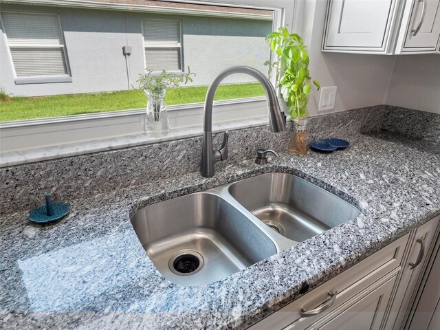 details with white cabinets, stone countertops, and sink