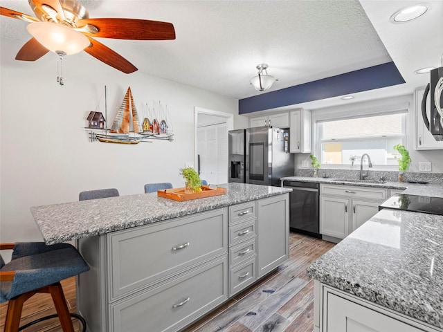 kitchen with a breakfast bar, light wood-type flooring, sink, a kitchen island, and stainless steel appliances