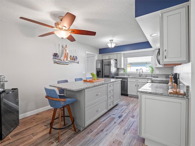 kitchen featuring a textured ceiling, appliances with stainless steel finishes, light hardwood / wood-style floors, and a center island