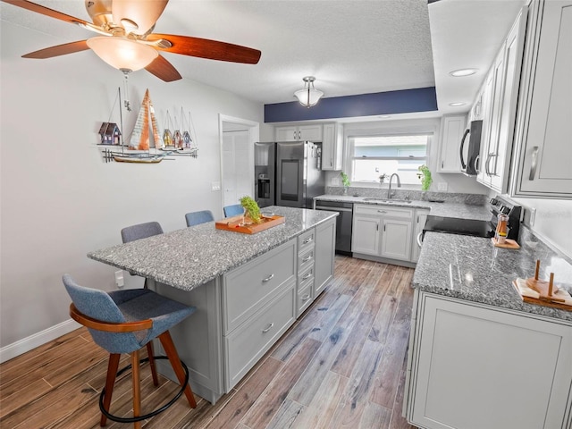 kitchen featuring a kitchen island, white cabinetry, stainless steel appliances, a kitchen breakfast bar, and light wood-type flooring