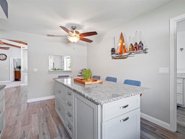 kitchen featuring a kitchen breakfast bar, a textured ceiling, light wood-type flooring, and a center island