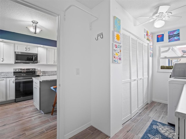 kitchen featuring appliances with stainless steel finishes, light hardwood / wood-style floors, white cabinetry, a textured ceiling, and ceiling fan