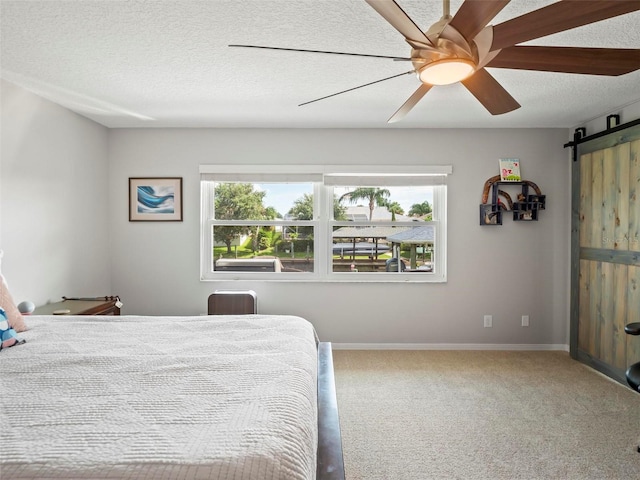 bedroom with ceiling fan, a textured ceiling, a barn door, and multiple windows