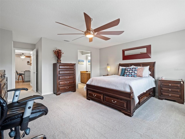 carpeted bedroom featuring a textured ceiling, ensuite bath, and ceiling fan