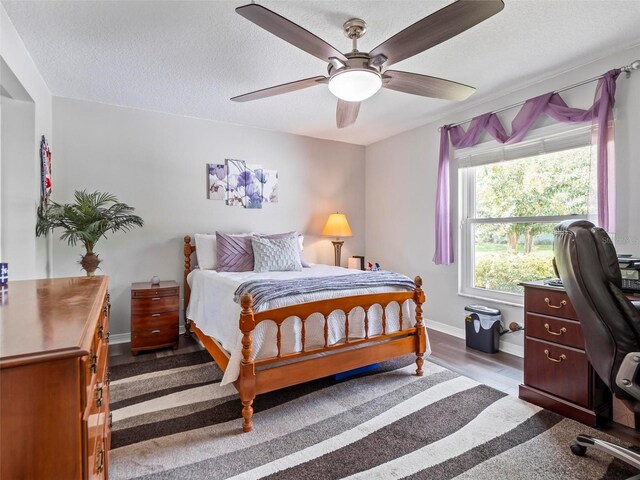 bedroom with ceiling fan, a textured ceiling, and hardwood / wood-style floors