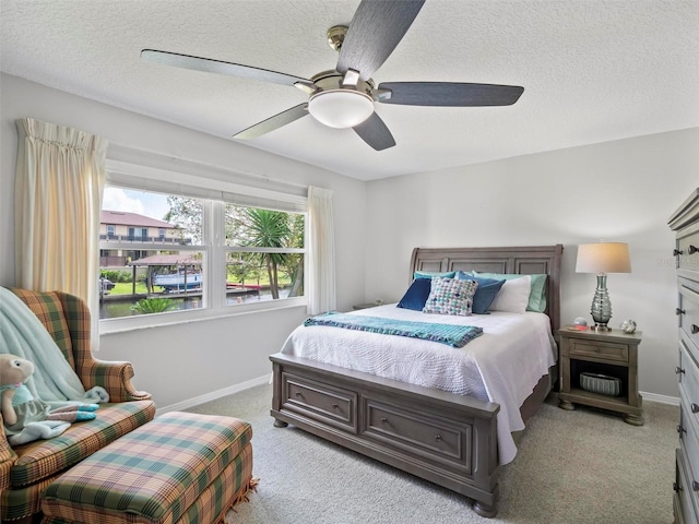 carpeted bedroom with ceiling fan and a textured ceiling