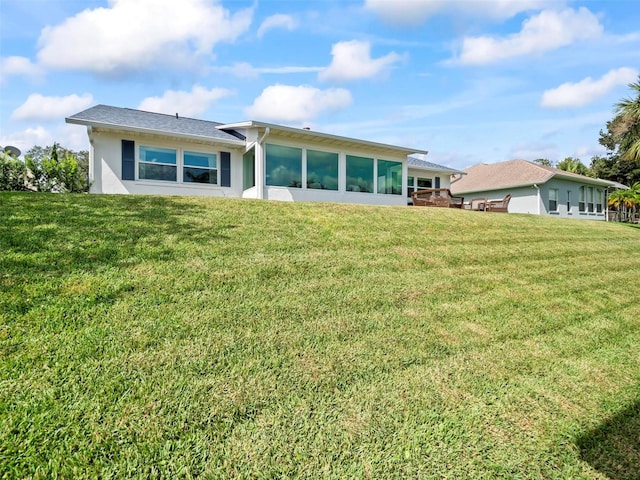 rear view of house featuring a sunroom and a lawn