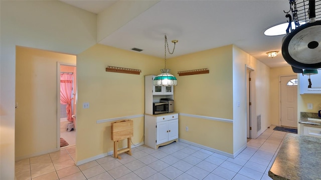 kitchen featuring white cabinetry, hanging light fixtures, and light tile patterned floors