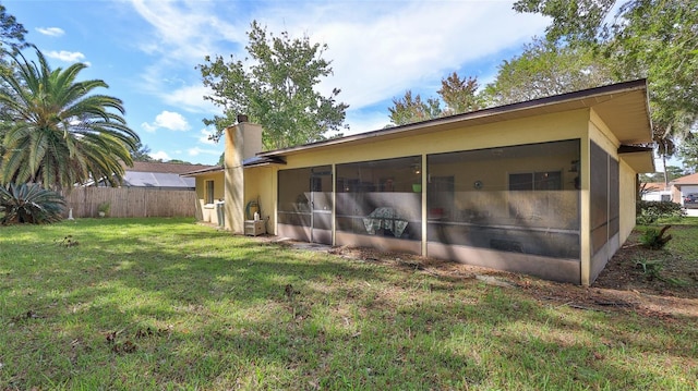 back of house featuring a sunroom and a lawn