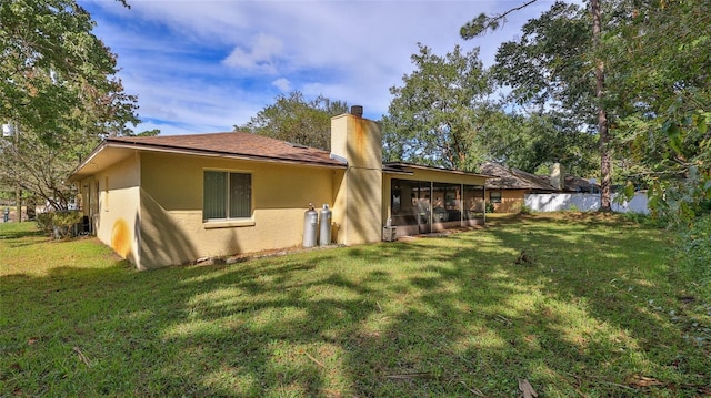 rear view of property with a sunroom and a yard