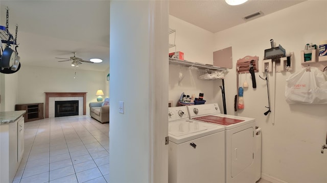 laundry room featuring ceiling fan, light tile patterned floors, a textured ceiling, a tiled fireplace, and washing machine and dryer