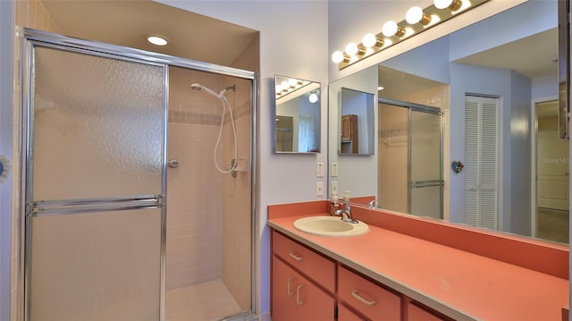 bathroom with a shower with shower door and vanity