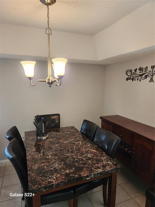 tiled dining area featuring a textured ceiling and a chandelier