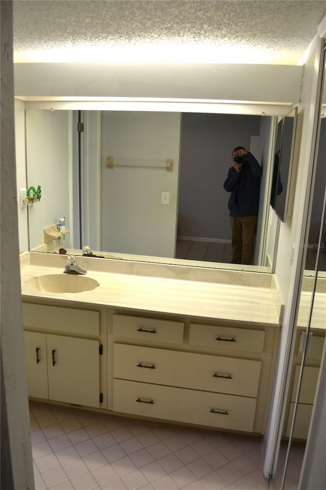 bathroom with tile patterned floors, vanity, and a textured ceiling